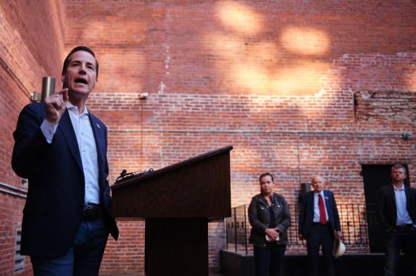 Moreno standing in a suit speaking at a lecturn with his finger raised